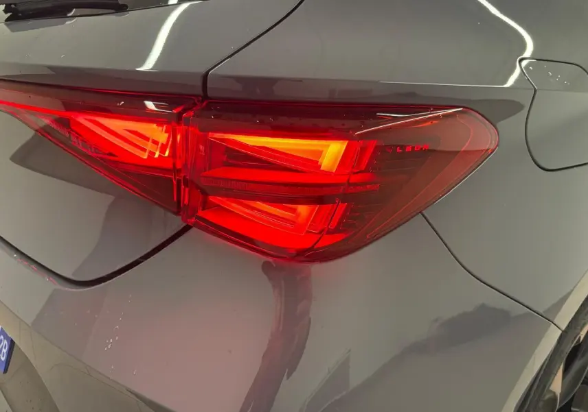 Gros plan sur le feu arrière droit rouge vif d'une CUPRA Leon 2025 gris Graphène avec jante cuivrée visible.