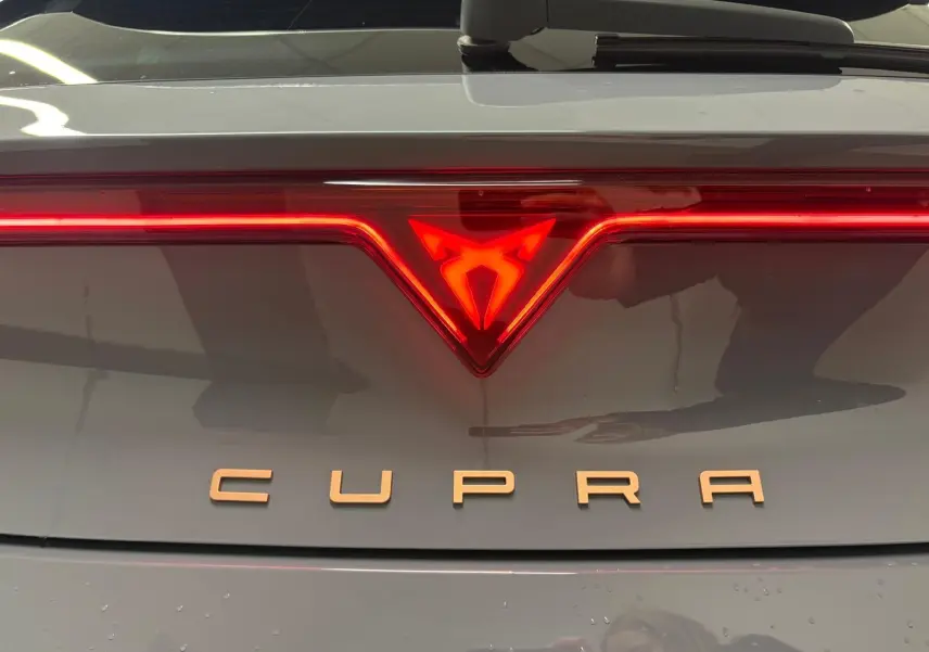 Gros plan sur le logo lumineux arrière rouge et l’inscription CUPRA sur la malle gris Graphène du Leon 2025.