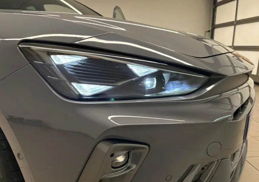 Gros plan sur le phare avant droit gris Graphène du CUPRA Leon 2025 avec éclairage LED et partie du pare-chocs visible.