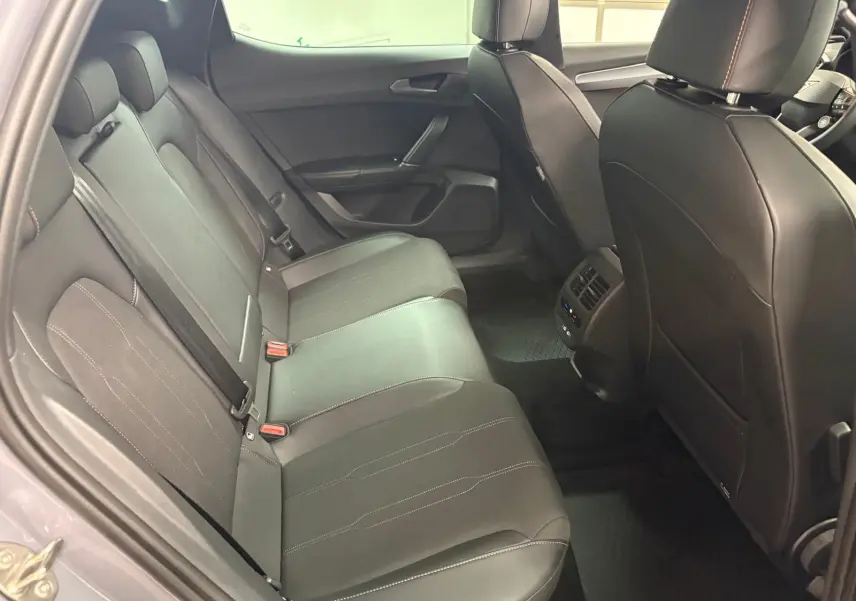 Vue intérieure arrière côté gauche de la CUPRA Leon Ph.2 gris Graphène, sièges en cuir noir avec surpiqûres contrastées.