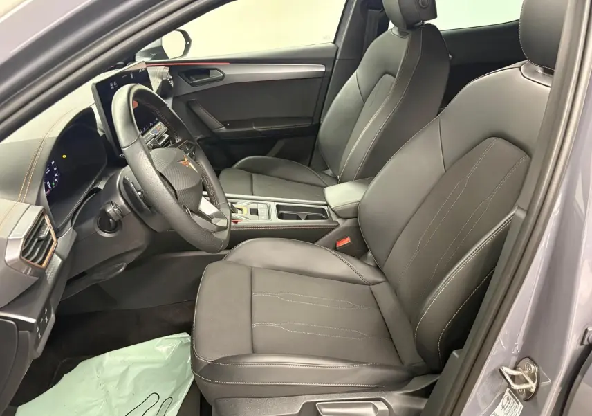 Vue intérieure côté conducteur de la CUPRA Leon 2025 gris Graphène, sièges cuir noirs avec surpiqûres contrastées.