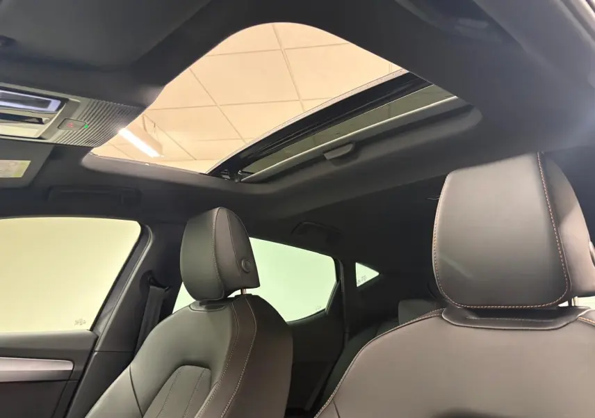 Vue intérieure du toit ouvrant panoramique et des sièges avant en cuir noir avec surpiqûres cuivrées d'une CUPRA Leon 2025.