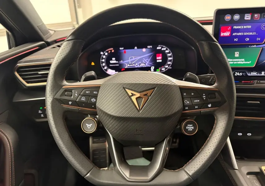 Vue rapprochée du volant cuir noir avec logo CUPRA cuivré et tableau de bord numérique de la CUPRA Leon 2025.