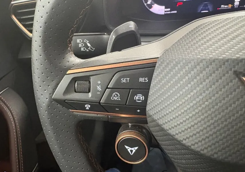 Gros plan sur le volant en cuir perforé gris avec surpiqûres cuivrées et commandes multifonctions du CUPRA Leon 2025.