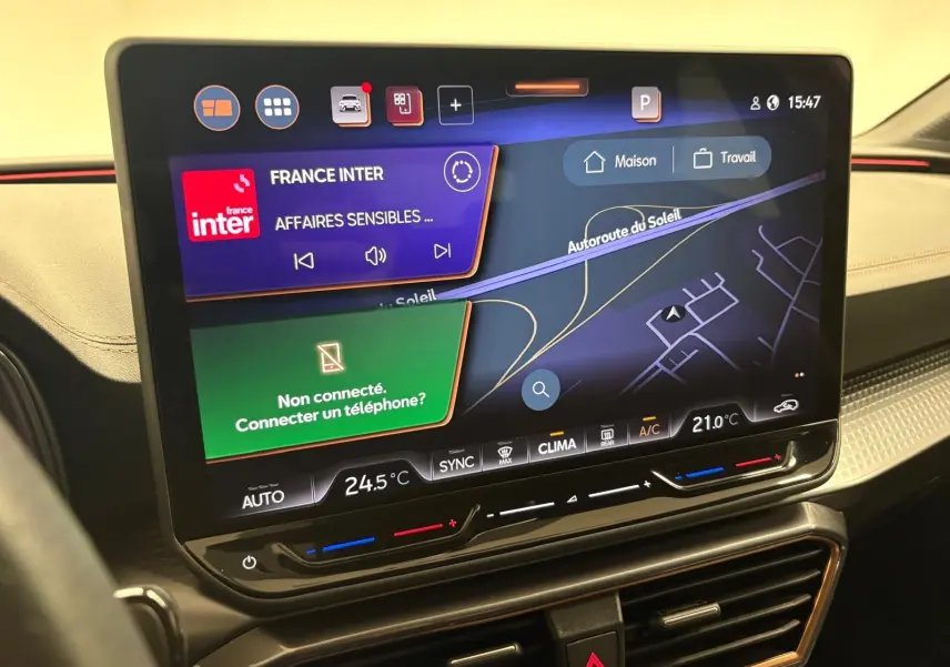 Écran central tactile du tableau de bord de la CUPRA Leon 2025, affichant navigation et radio, avec commandes climatisation intégrées.
