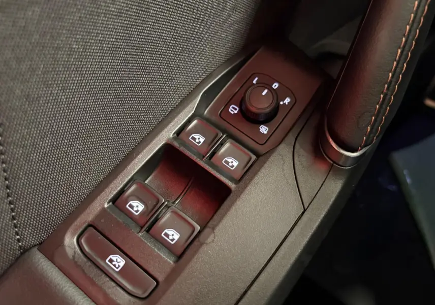 Gros plan sur la commande des vitres électriques et rétroviseurs côté conducteur du CUPRA Leon 2025, finition cuir noir.