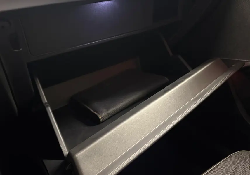 Gant de boîte à gants ouvert dans l'habitacle sombre d'une CUPRA Leon 2025, détail intérieur sobre.