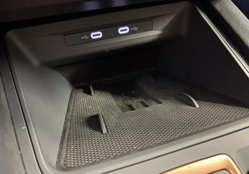 Gros plan sur la zone de recharge sans fil et ports USB lumineux dans l'habitacle noir du CUPRA Leon 2025.