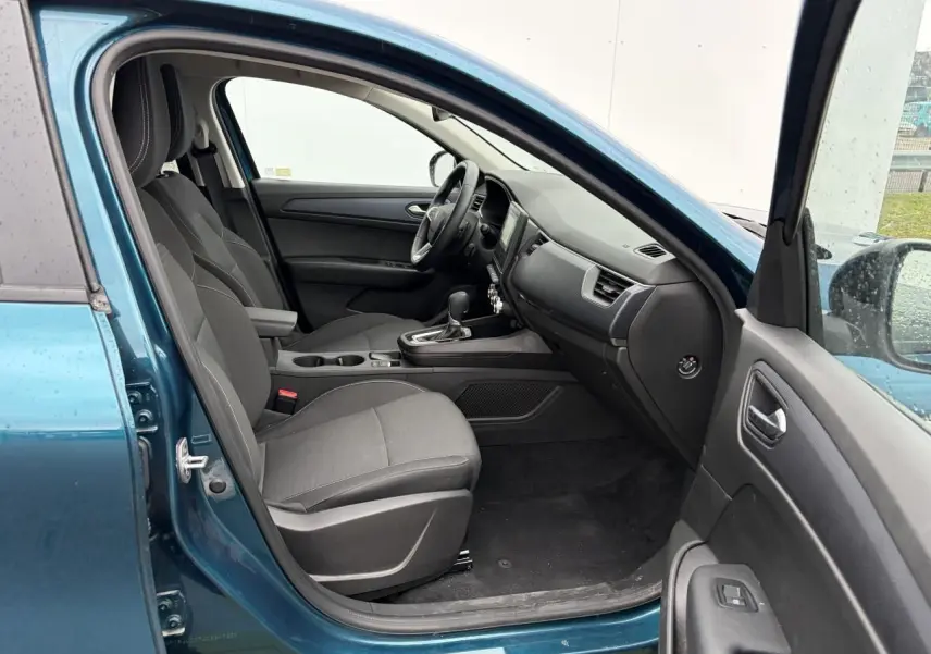 Vue intérieure côté conducteur d'une Renault Arkana 2025 bleu Zanzibar, sièges tissu gris et console centrale avec boîte auto.