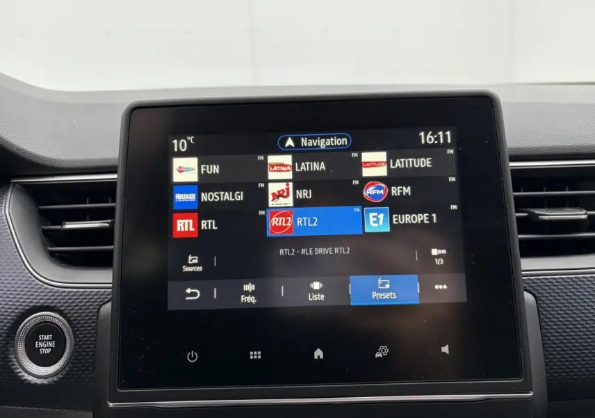Écran tactile central de la Renault Arkana 2025 affichant les stations radio, entouré de la console noire texturée.