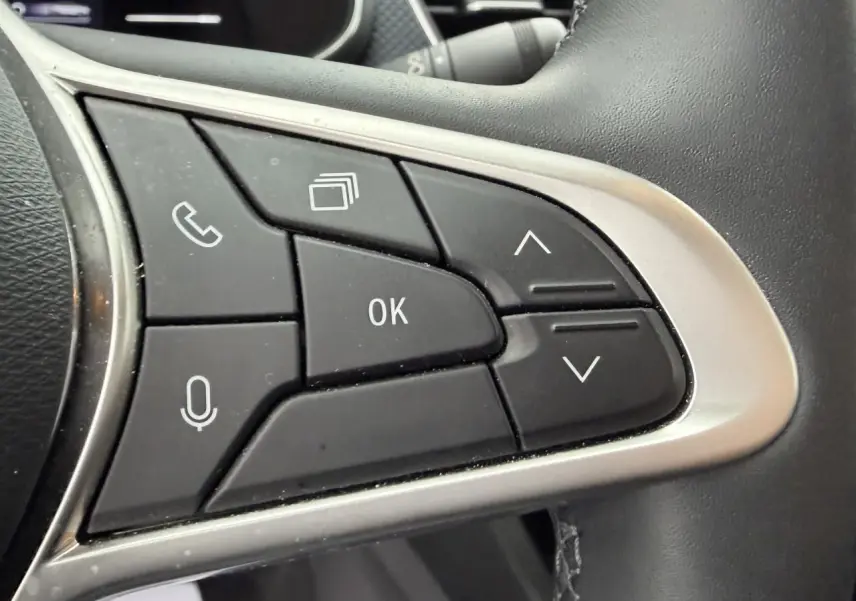 Gros plan sur les commandes au volant à droite du Renault Arkana 2025, boutons noirs avec cadre argenté.