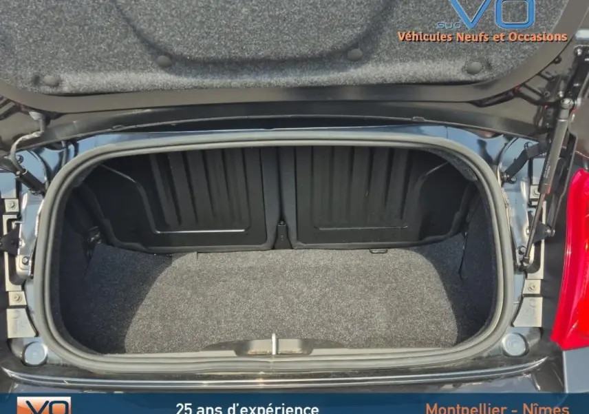 Coffre ouvert vu de dessus d'une FIAT 500C noire 2024, montrant l'espace de rangement vide et la garniture intérieure.