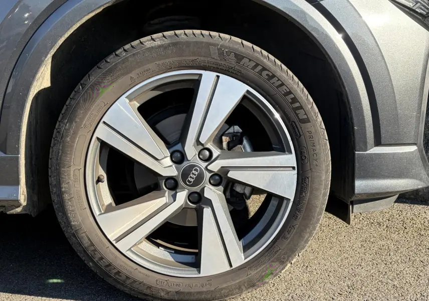 Gros plan sur la roue avant droite avec jante alliage 18 pouces et carrosserie gris Daytona nacré d’un Audi Q2 2024.