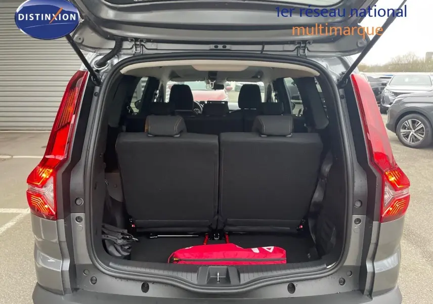 Vue arrière ouverte du Dacia Jogger gris schiste métal 2026, montrant les sièges arrière et un objet rouge dans le coffre.