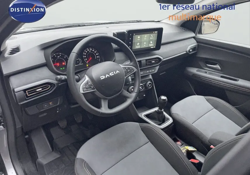 Vue intérieure côté conducteur du Dacia Jogger gris schiste, montrant le tableau de bord, volant multifonction et console centrale avec boîte manuelle.