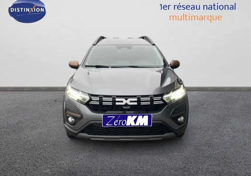 Vue avant d'un Dacia Jogger gris schiste métal 2026 avec phares allumés et calandre noire distinctive.