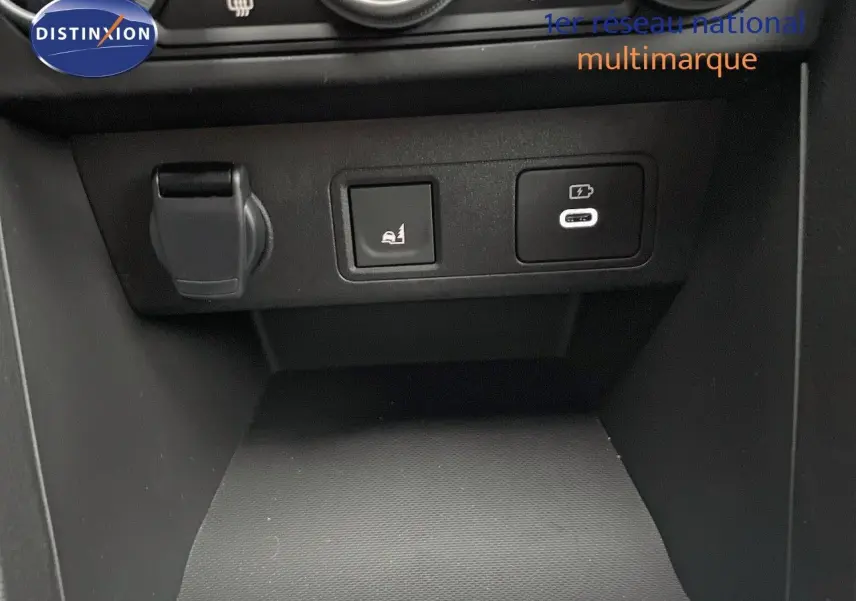 Gros plan sur la console centrale du Dacia Jogger 2026, montrant prises USB et bouton d'assistance au stationnement.