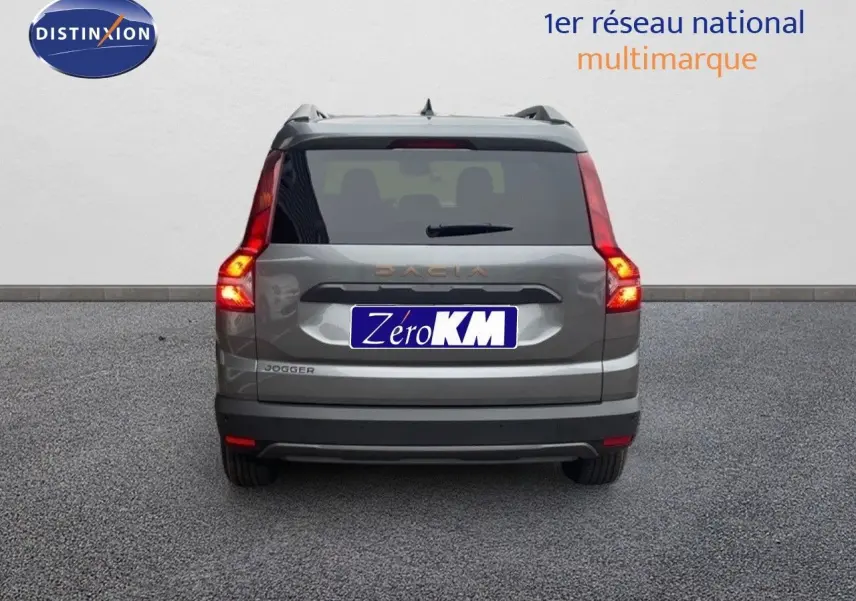 Vue arrière d'un Dacia Jogger gris schiste métal avec feux allumés, sur fond neutre en extérieur.