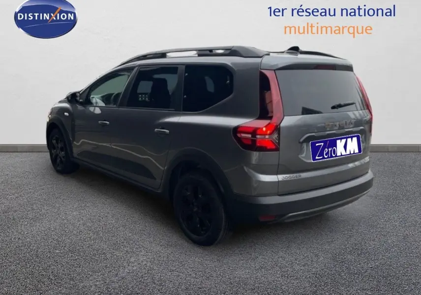 Vue 3/4 arrière droite d'un Dacia Jogger gris schiste métal avec feux arrière allumés et jantes noires.