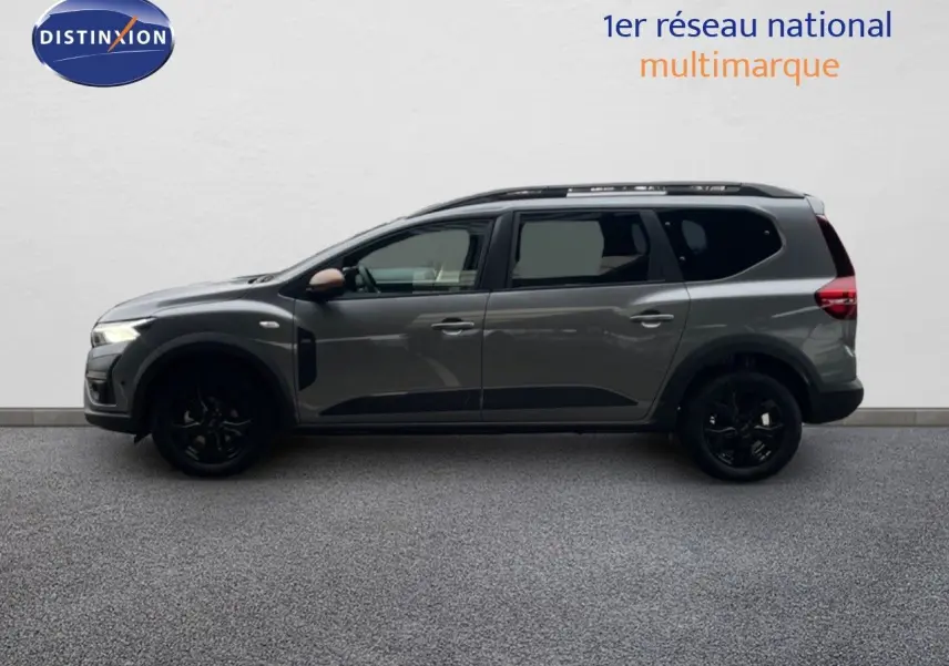 Vue de profil côté gauche du Dacia Jogger gris schiste métallisé avec jantes noires et barres de toit.