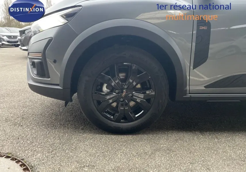 Gros plan sur la roue avant droite et la partie avant grise métallisée du Dacia Jogger 2026 avec jante noire et badge Extreme.