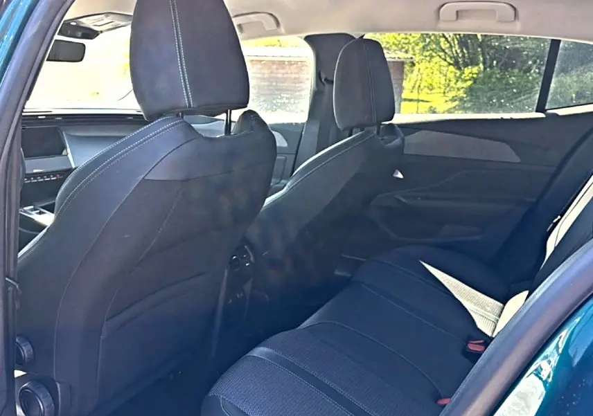 Vue intérieure arrière côté gauche du Peugeot 408 Hybrid 145 allure bleu, montrant les sièges et la banquette tissu noir.