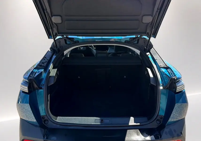 Coffre ouvert vu de l'arrière d'une Peugeot 408 Hybrid 145 allure bleu, montrant l'espace de chargement vide.