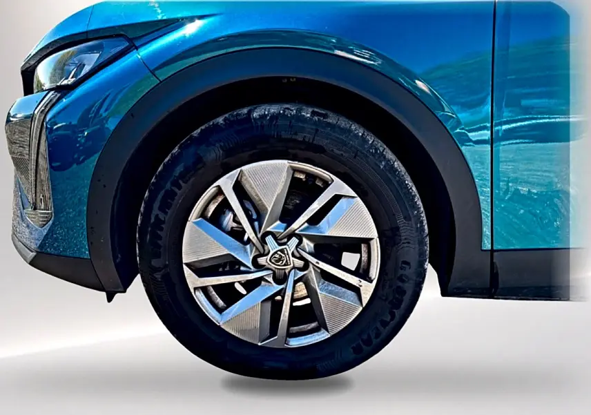 Gros plan sur la roue avant gauche d’une Peugeot 408 Hybrid 145 allure e-dcs6 bleu avec jante alu au design moderne.
