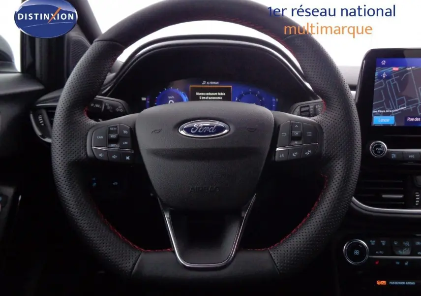 Vue rapprochée du volant perforé avec surpiqûres rouges et tableau de bord numérique de la Ford Puma gris Solar Metal 2022.