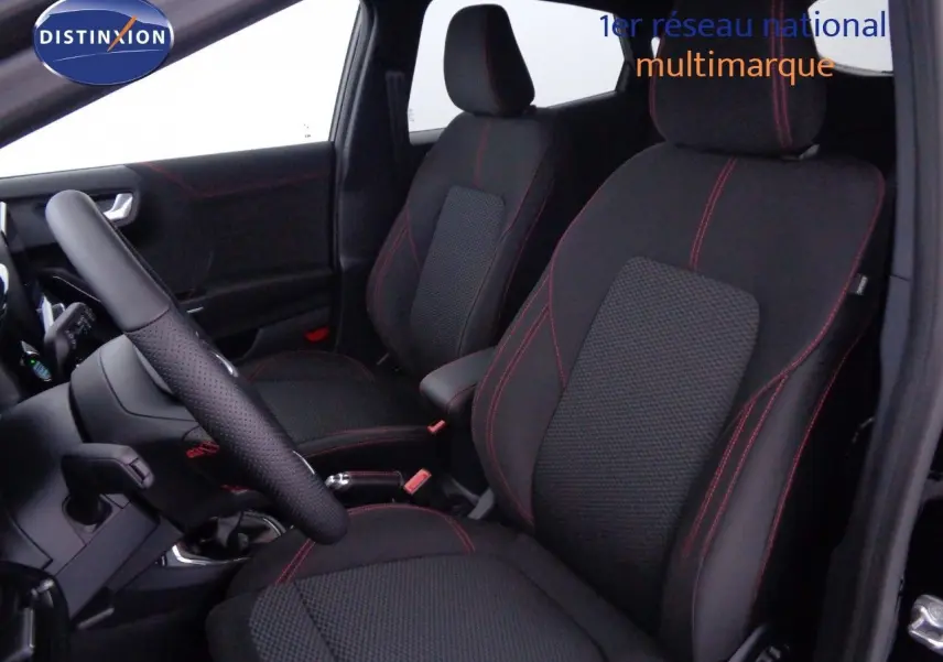Vue intérieure côté conducteur du Ford Puma 2022, sièges noirs avec surpiqûres rouges et volant cuir perforé.