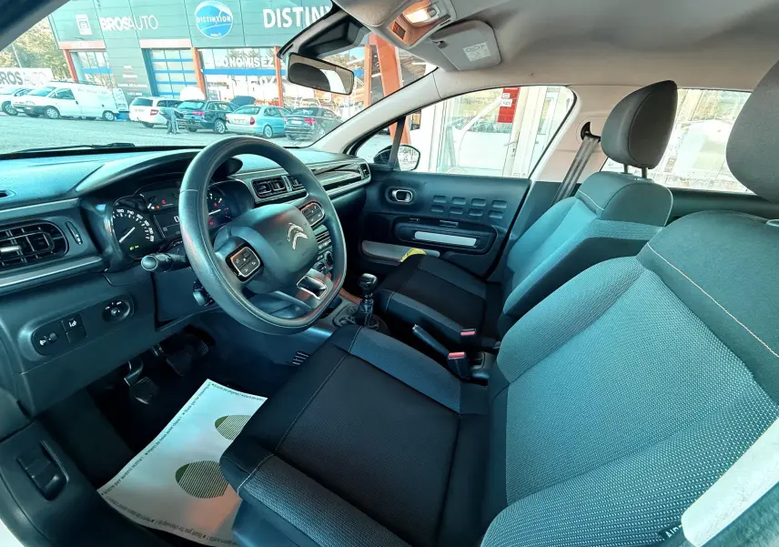 Intérieur de la Citroën C3 2021 vu côté conducteur, sièges tissu gris-noir et tableau de bord noir.