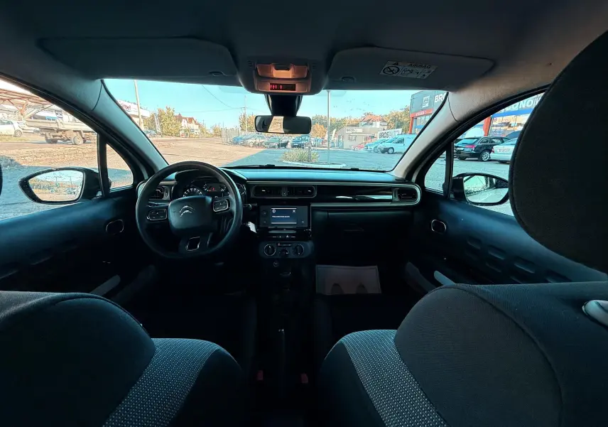 Vue intérieure avant du tableau de bord et volant d'une Citroën C3 1.5 BlueHDi 2021 avec sièges tissu gris-noir.