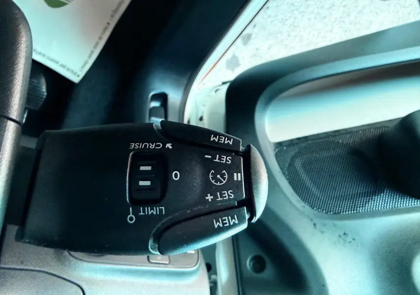 Gros plan sur la commande de régulateur de vitesse à gauche du volant dans une Citroën C3 blanche de 2021.