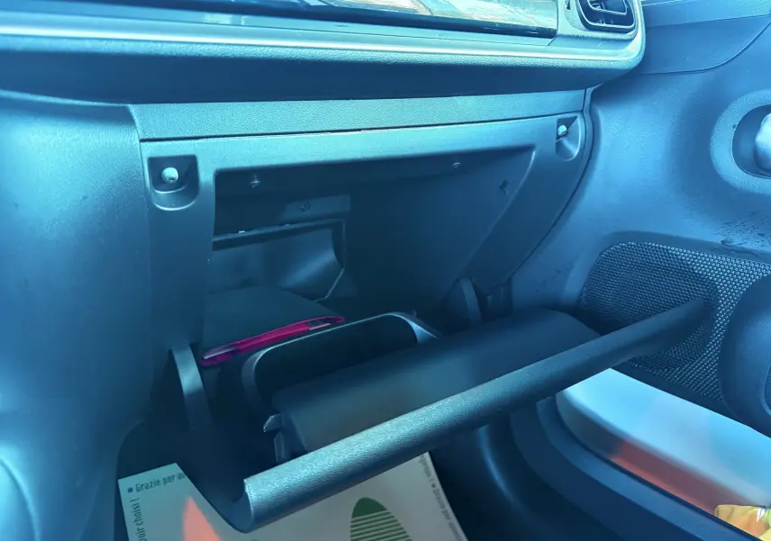 Gros plan sur la boîte à gants ouverte côté passager d'une Citroën C3 1.5 BlueHDi blanche, intérieur gris noir.