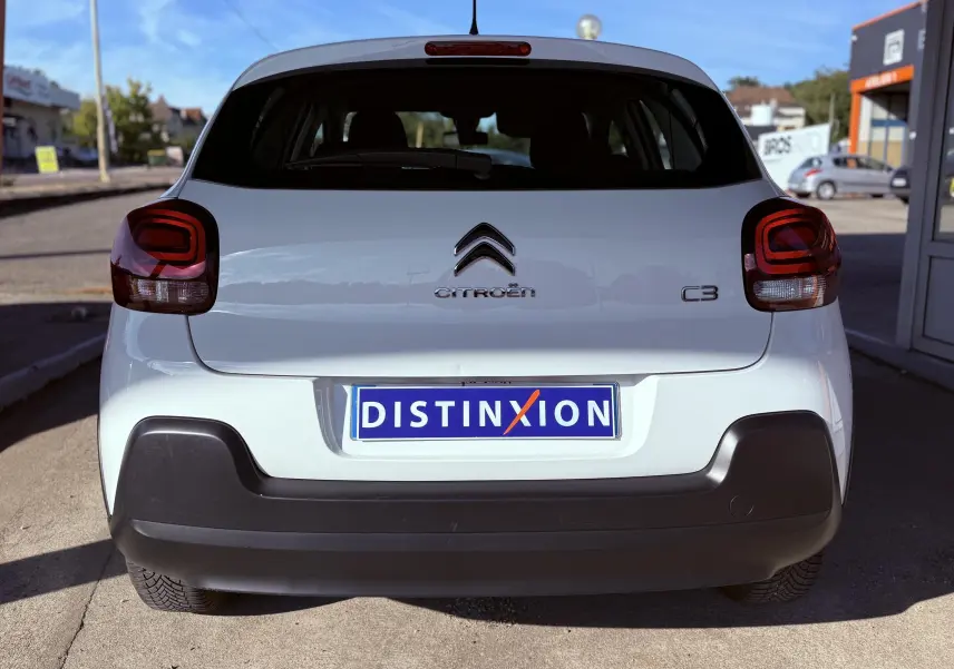 Vue arrière d'une Citroën C3 blanche de 2021 avec feux arrière rouges et plaque d'immatriculation Distinxion.