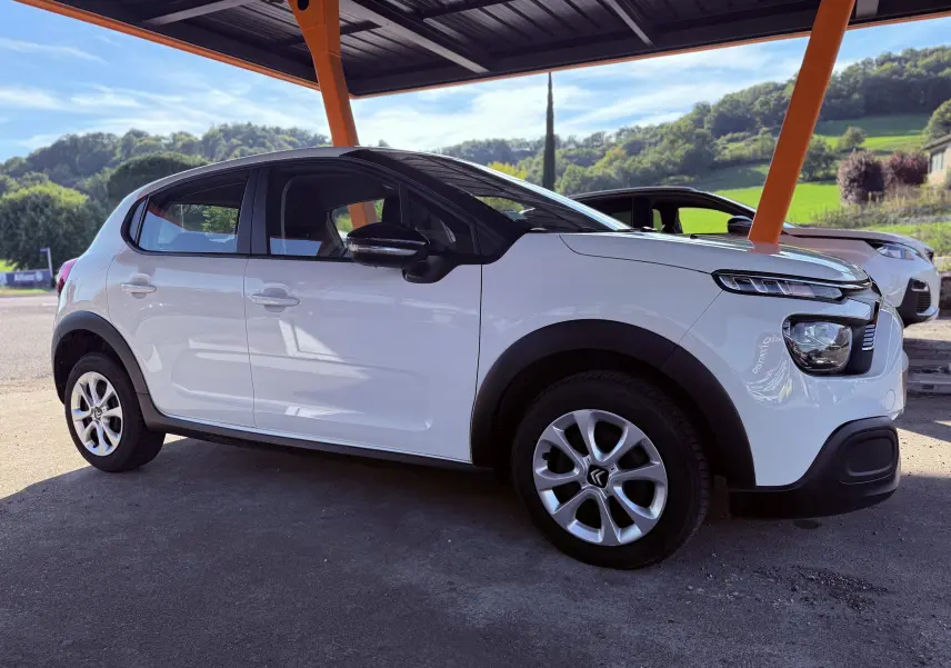 Citroën C3 blanc vue de profil côté gauche sous abri avec jantes alliage et protections noires sur les passages de roue
