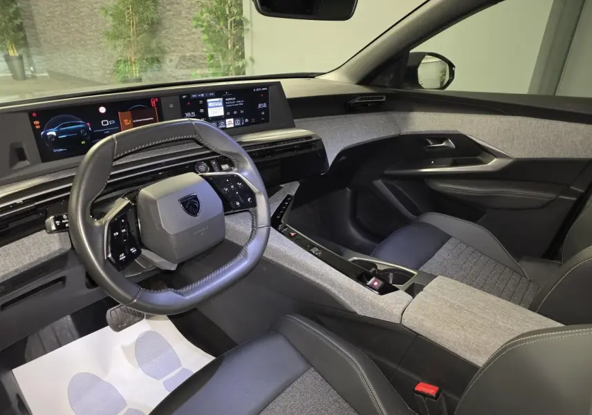 Vue intérieure avant droite du Peugeot 3008 gris, avec tableau de bord numérique et volant compact cuir noir.