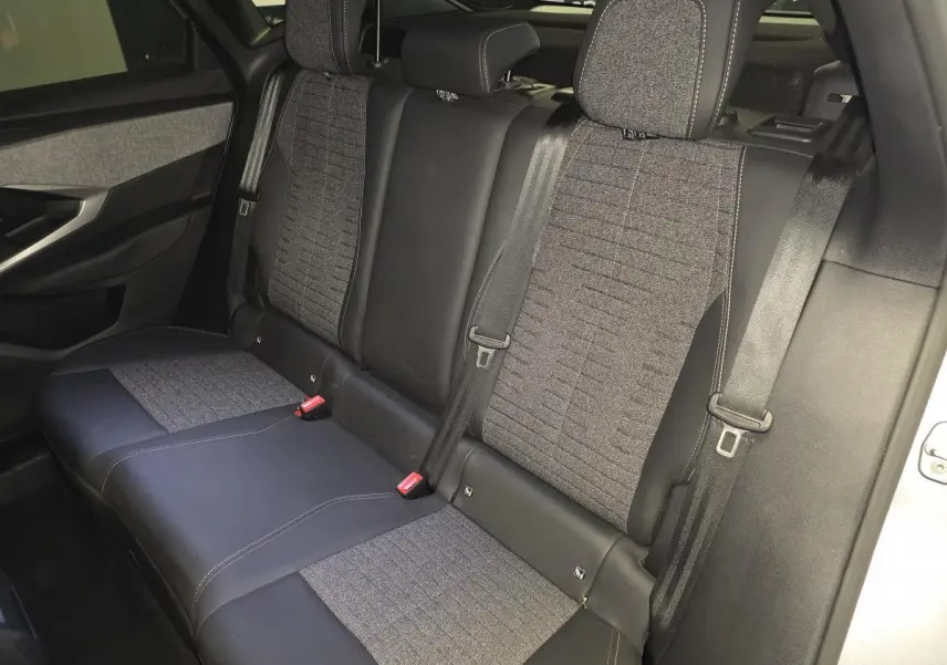 Vue intérieure de la banquette arrière du Peugeot 3008 hybride 2025, sellerie tissu gris et cuir noir.