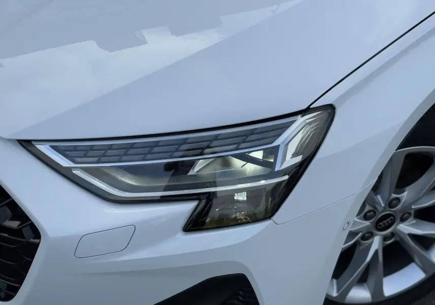 Gros plan sur le phare Matrix LED avant droit et la jante alliage 17 pouces d'une Audi A3 Sportback Blanc Arkona 2024.