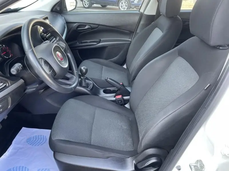 Intérieur de la Fiat Tipo 2019 blanc, vue côté conducteur montrant sièges noirs et levier de vitesse manuel.