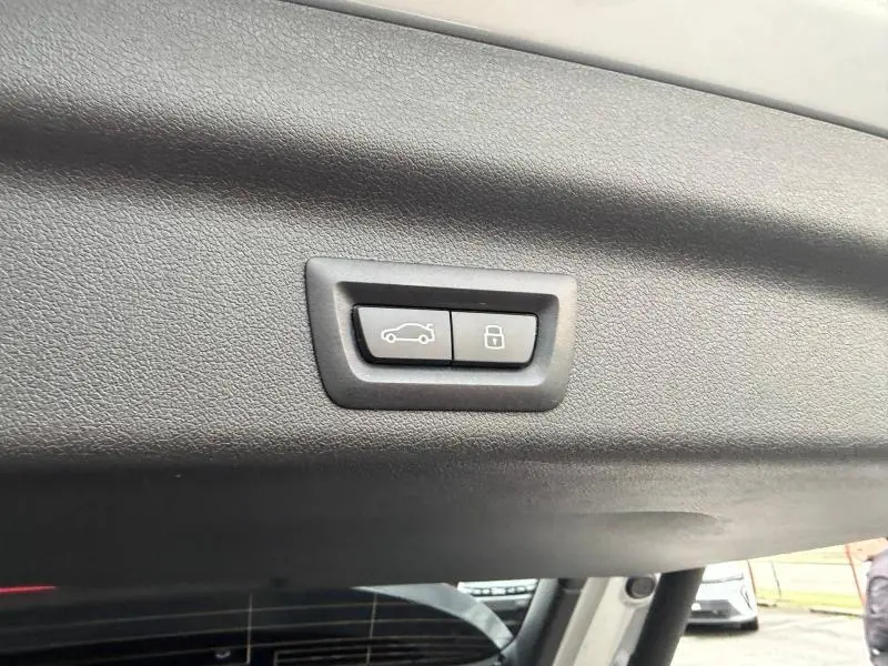 Boutons de commande d'ouverture et de verrouillage du coffre sur la garniture intérieure arrière du BMW X1 Spacesilber métal.