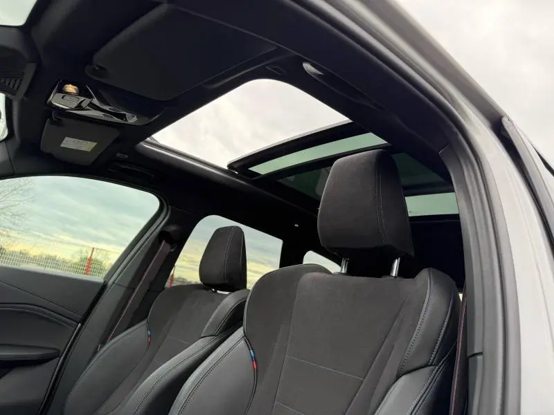 Vue intérieure côté conducteur du BMW X1 XDrive20d 2025 avec sièges sport en alcantara noir et toit ouvrant panoramique.