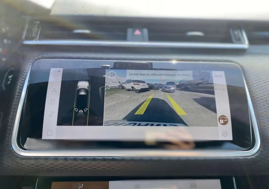 Écran tactile intérieur du Range Rover Velar 2022 montrant la caméra de recul avec guidage jaune sur route.