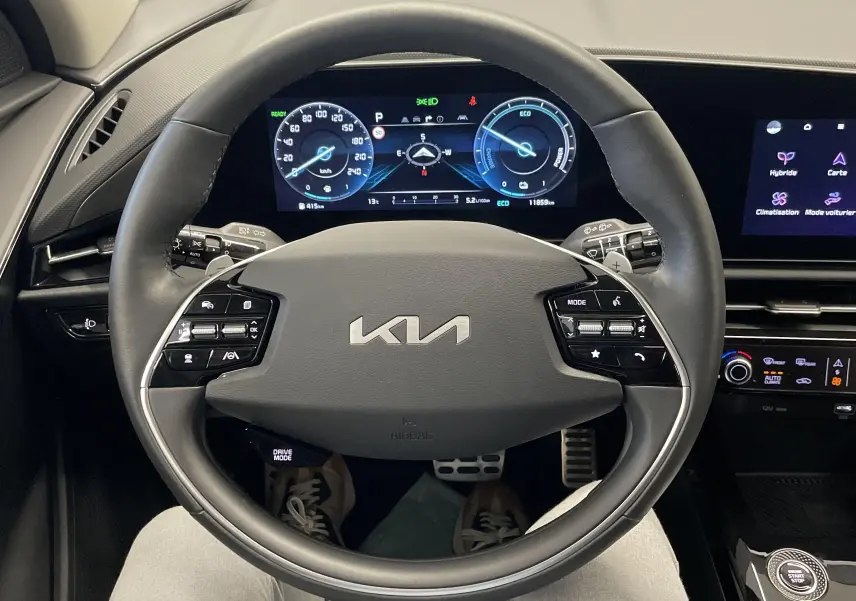 Vue intérieure centrée sur le volant KIA du Niro 2025, avec tableau de bord numérique et écran tactile multifonction.