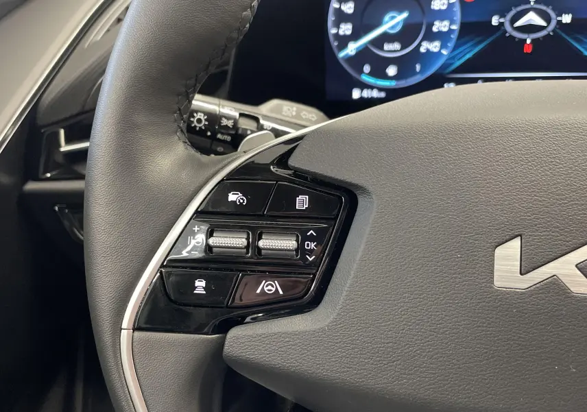 Gros plan sur la partie gauche du volant noir du KIA NIRO 2025 avec commandes de régulateur et logo KIA visible.
