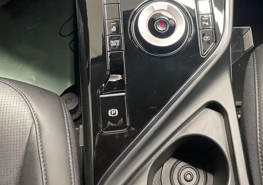 Console centrale noire avec molette de sélection et boutons de frein à main dans l'habitacle du Kia Niro hybride 2025.