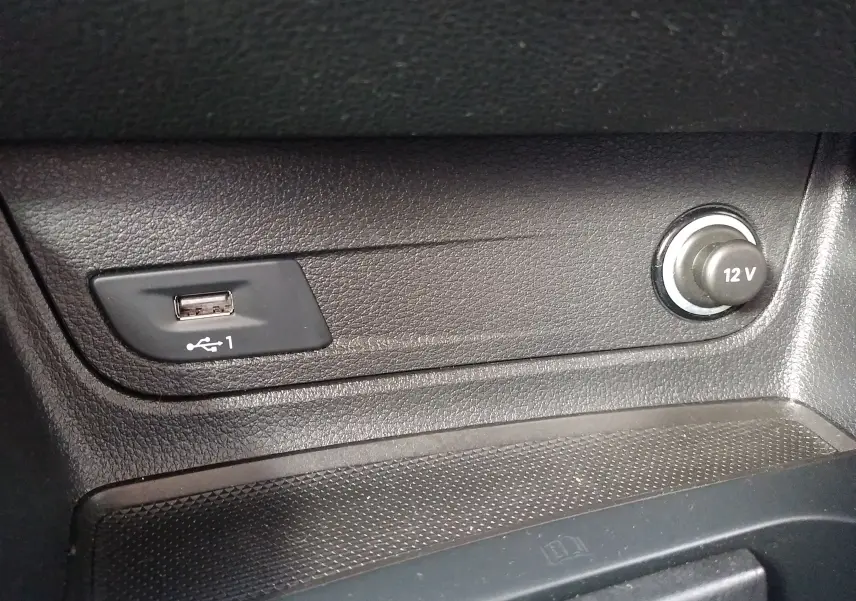 Prise USB et allume-cigare 12V en gros plan sur la console centrale noire d'un Audi Q2 2023.