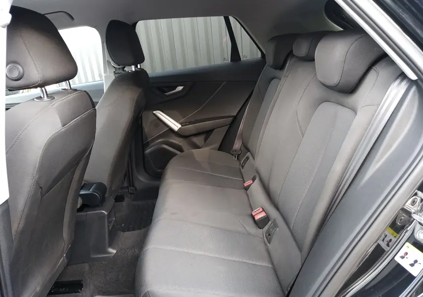 Vue intérieure côté droit des sièges arrière gris tissu de l'Audi Q2 35 TFSI S-Line 2023 noir mito metal.