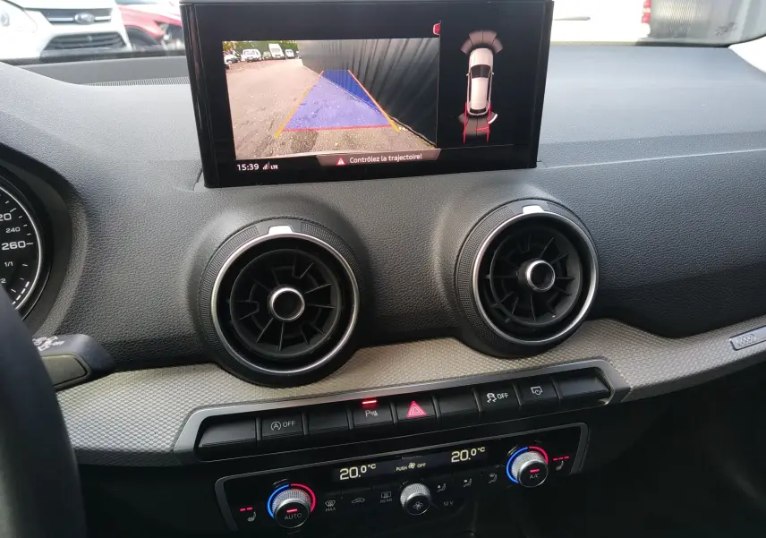 Intérieur de l'Audi Q2 35 TFSI S-Line 2023, tableau de bord avec écran de recul et aérateurs ronds noirs.