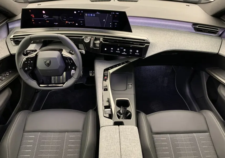 Vue intérieure avant du Peugeot 3008 Hybrid 145 GT, planche de bord grise avec éclairage d'ambiance violet et volant compact noir.
